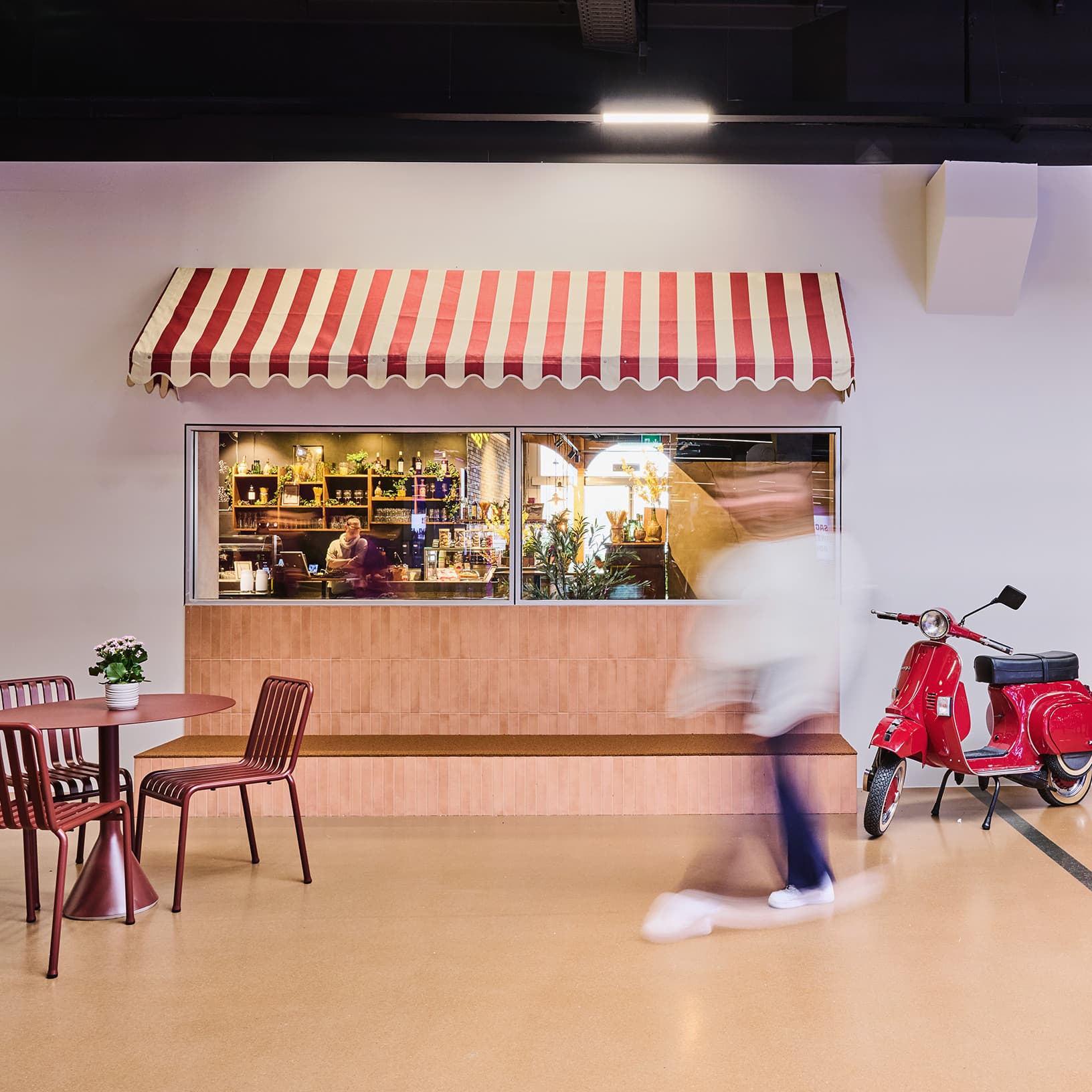  Italienisch gestalteter Gastronomiebereich bei Piazza Meraviglia in The Yards mit rot-weissen Markisen, roter Vespa und Sitzplätzen.