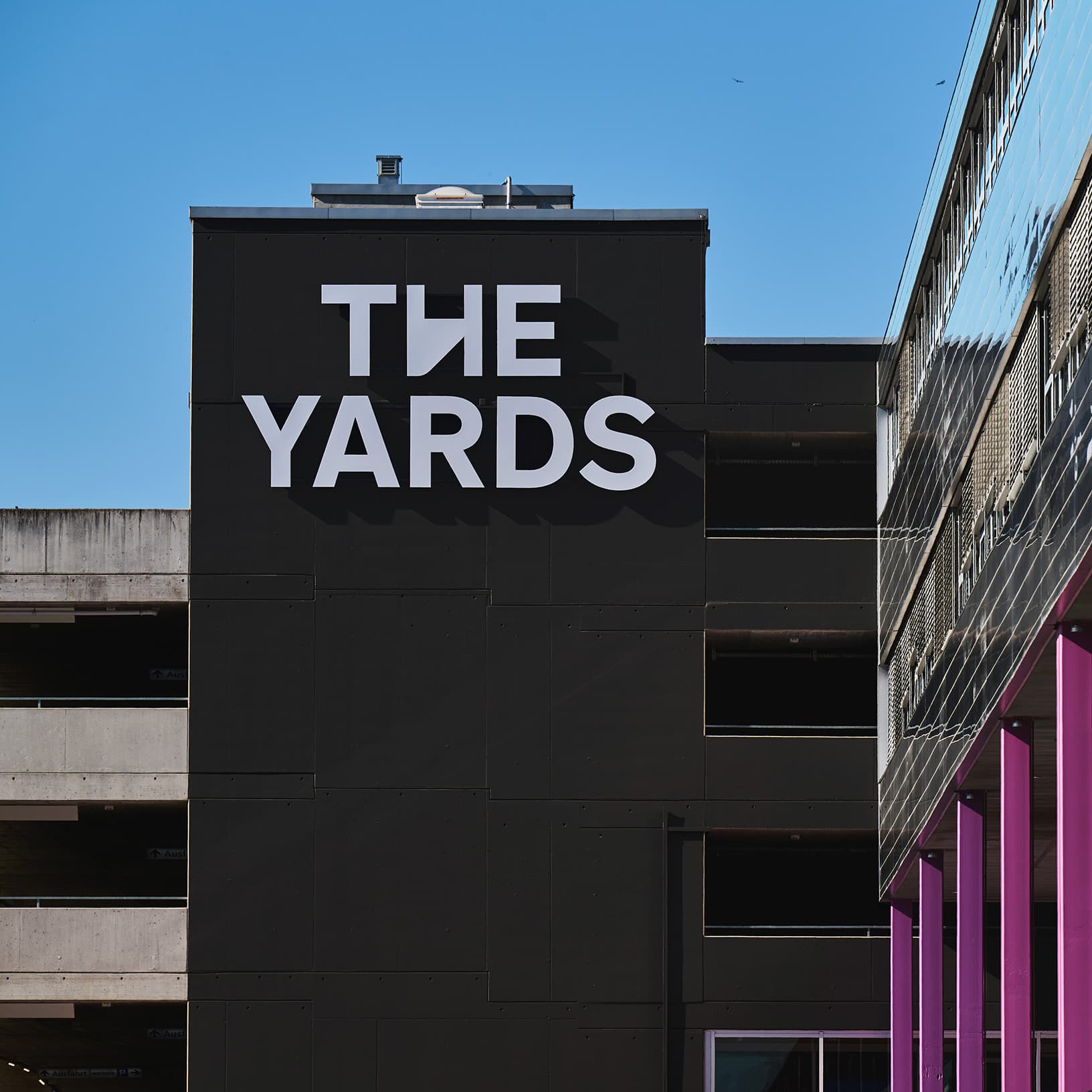 Grosses weisses The Yards Logo an der schwarzen Gebäudefassade des Erlebnis- und Einkaufscenters in Rümlang.