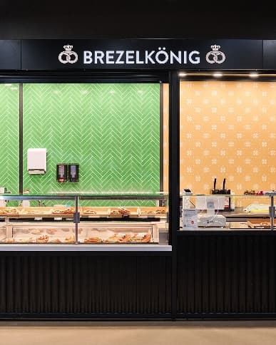 Brezelkönig Shop & Café bei The Yards mit grüner Rückwand und Brezeln in der Verkaufstheke.
