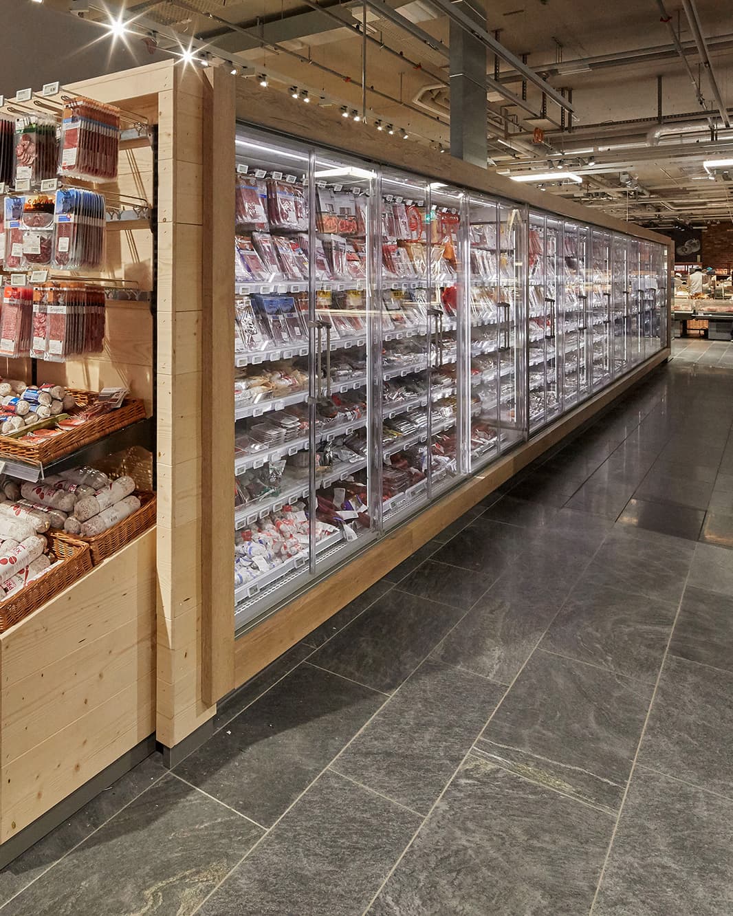 Langes Kühlregal mit verpackten Fleisch- und Wurstwaren im Coop Supermarkt bei The Yards in Rümlang.