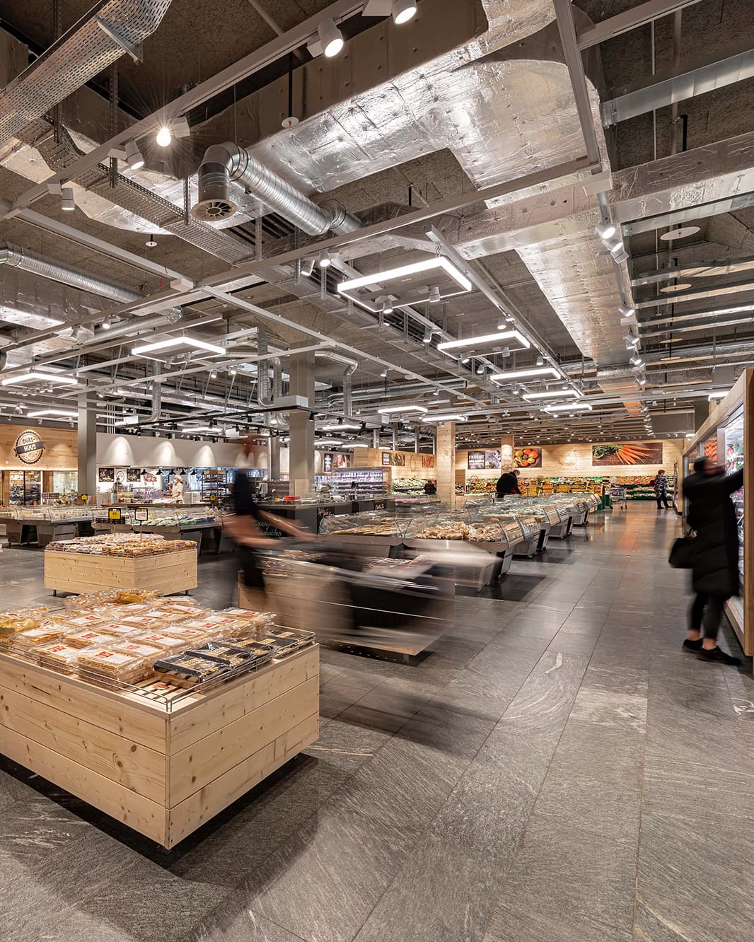 Übersicht der grosszügigen Verkaufsfläche des Coop Supermarkts bei The Yards mit Holzpräsentationen und Frischetheken.