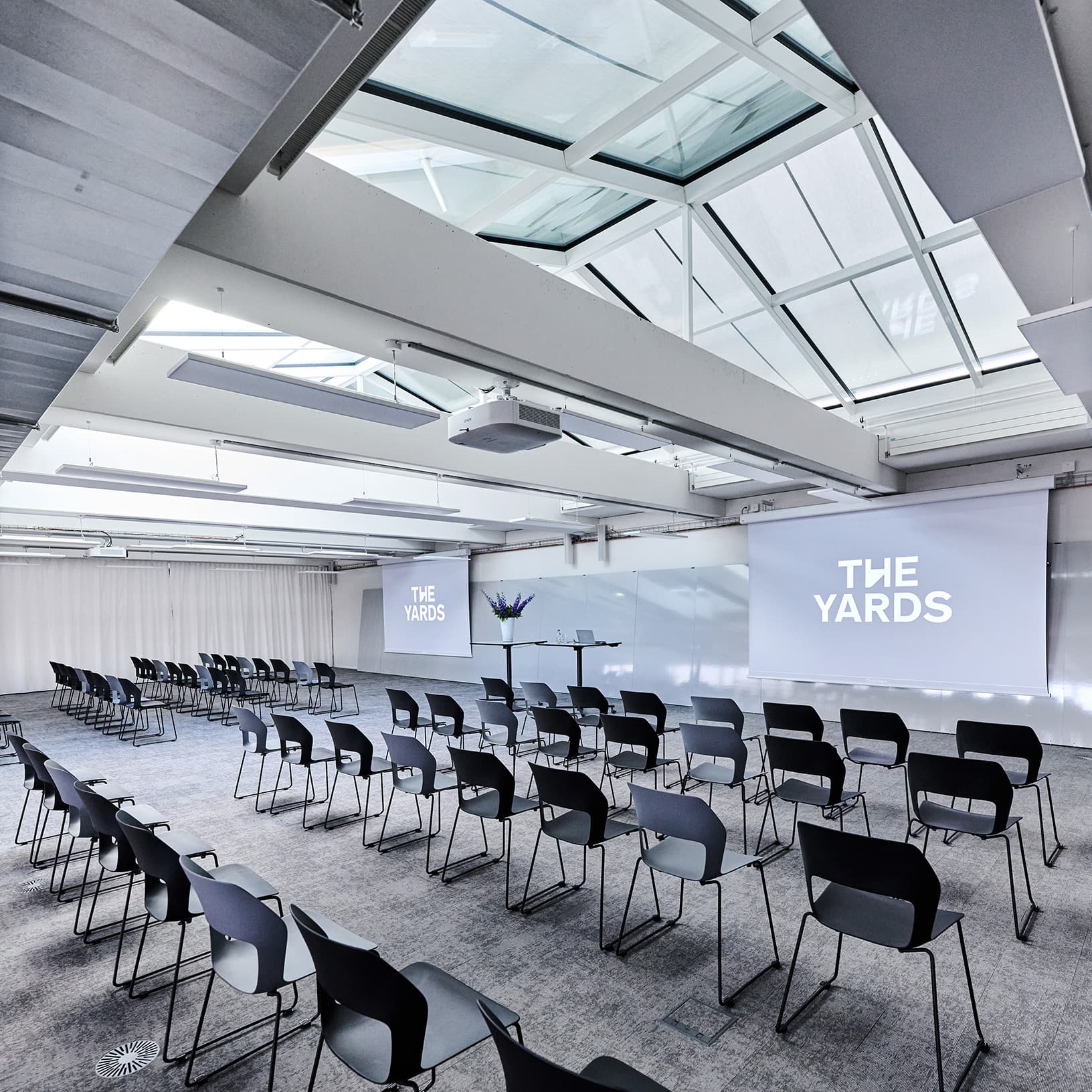 Lichtdurchfluteter Konferenzsaal von The Yards Events mit Bestuhlung, Leinwänden und Tageslicht.