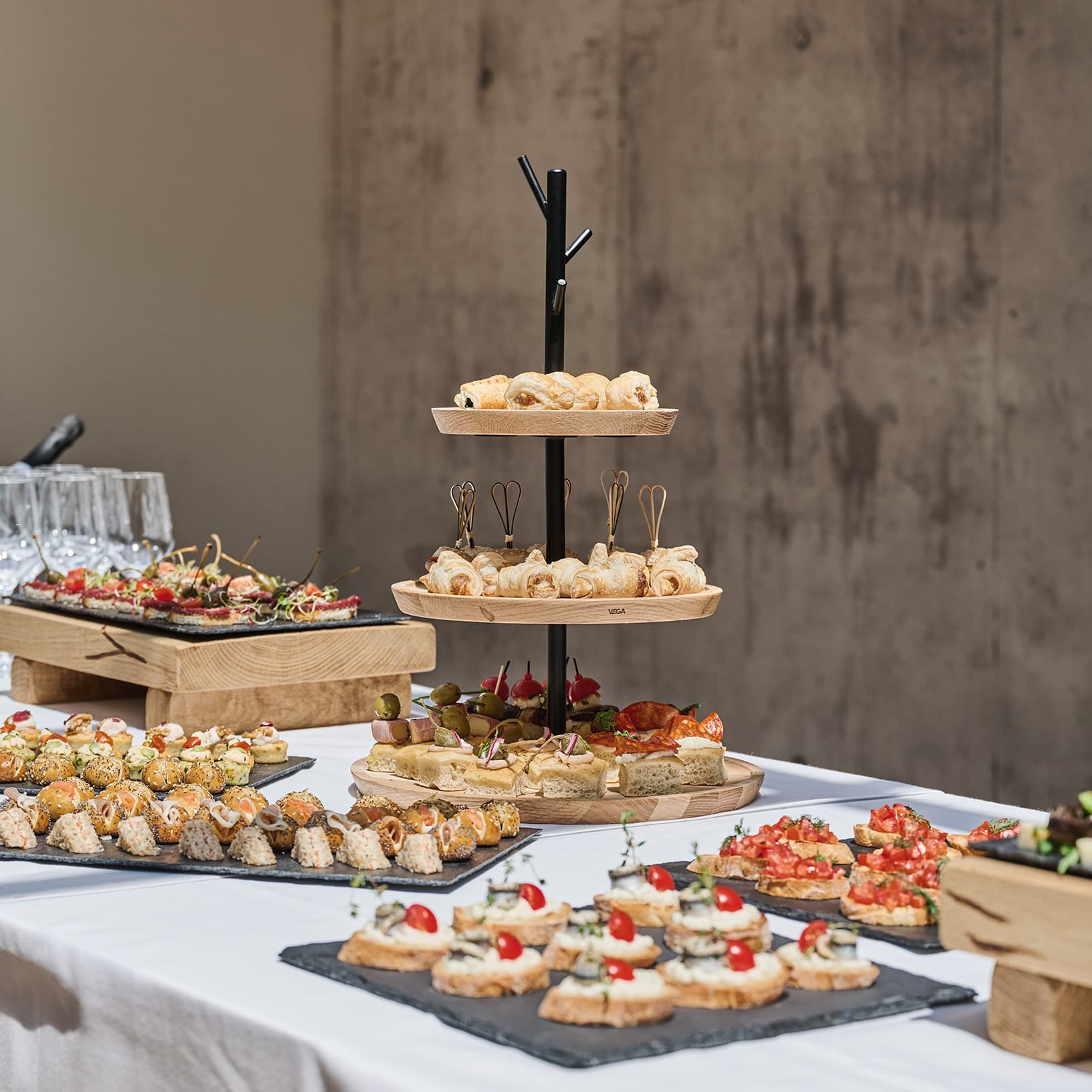 Apérobuffet mit verschiedenen Fingerfood-Häppchen auf Etageren und Servierplatten bei The Yards Events.