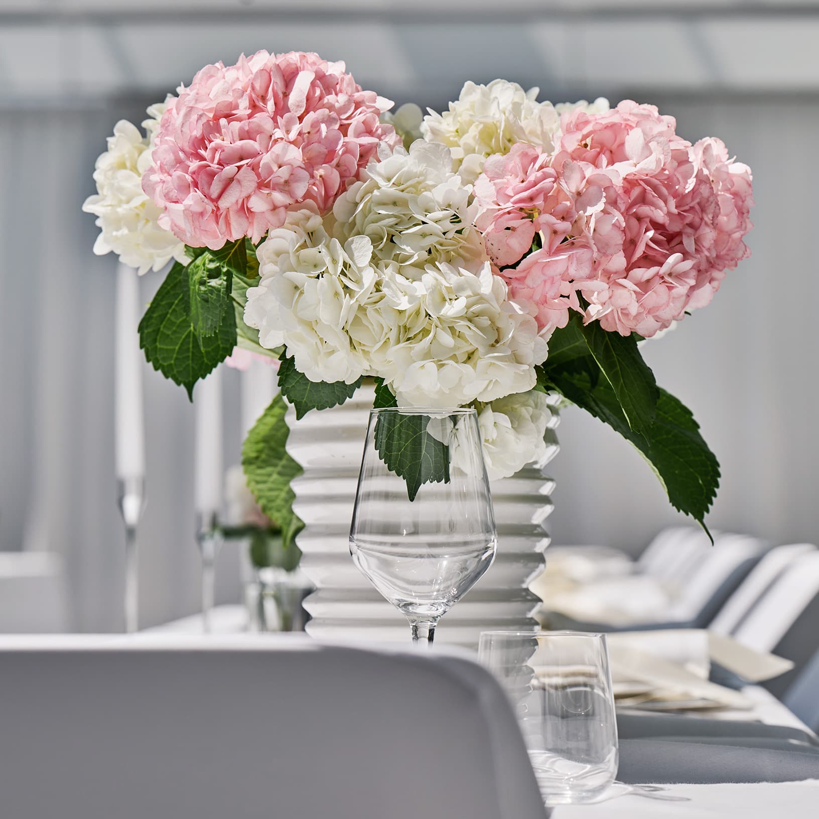 Festliche Tischdekoration mit weissen Kerzen, Blumengestecken und Weingläsern bei The Yards Events.