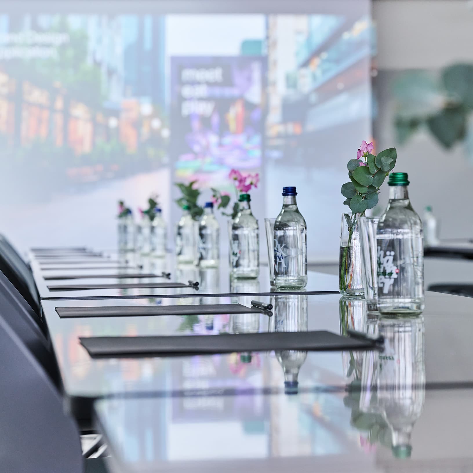 Gedeckte Seminartische mit Wasserflaschen, Schreibunterlagen und Blumen für eine Tagung bei The Yards Events.