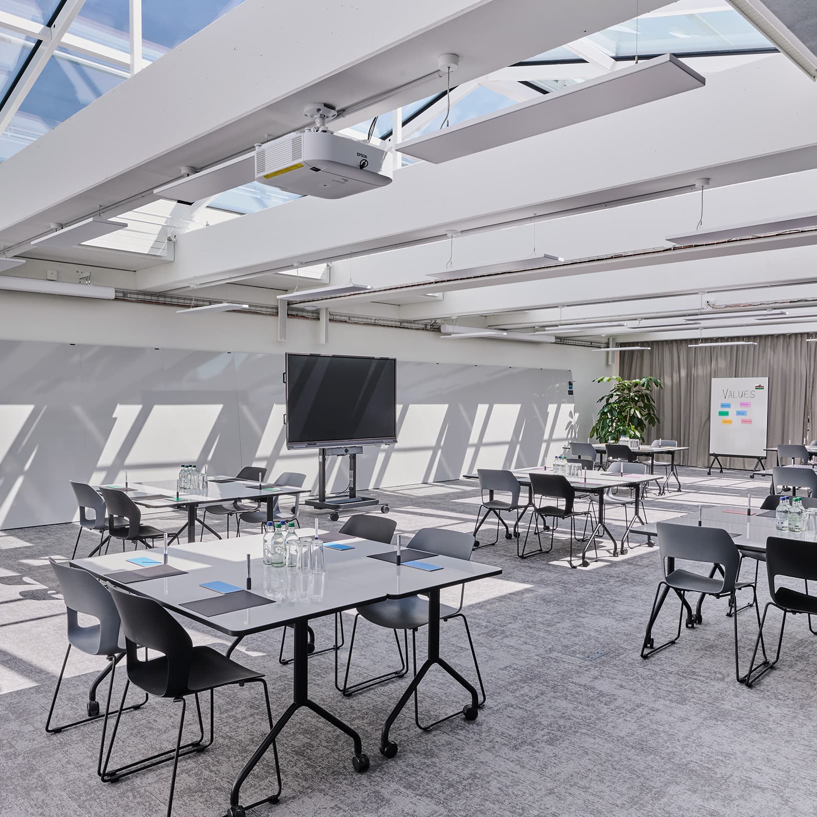 Heller Workshopraum mit Gruppentischen, Whiteboard und Präsentationstechnik bei The Yards Events.
