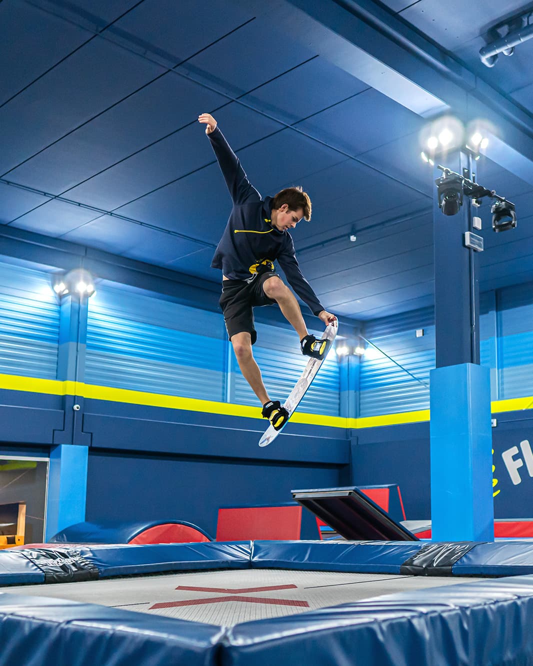 Jugendlicher macht einen Sprung mit einem Board über dem Trampolin im Flip Lab bei The Yards.
