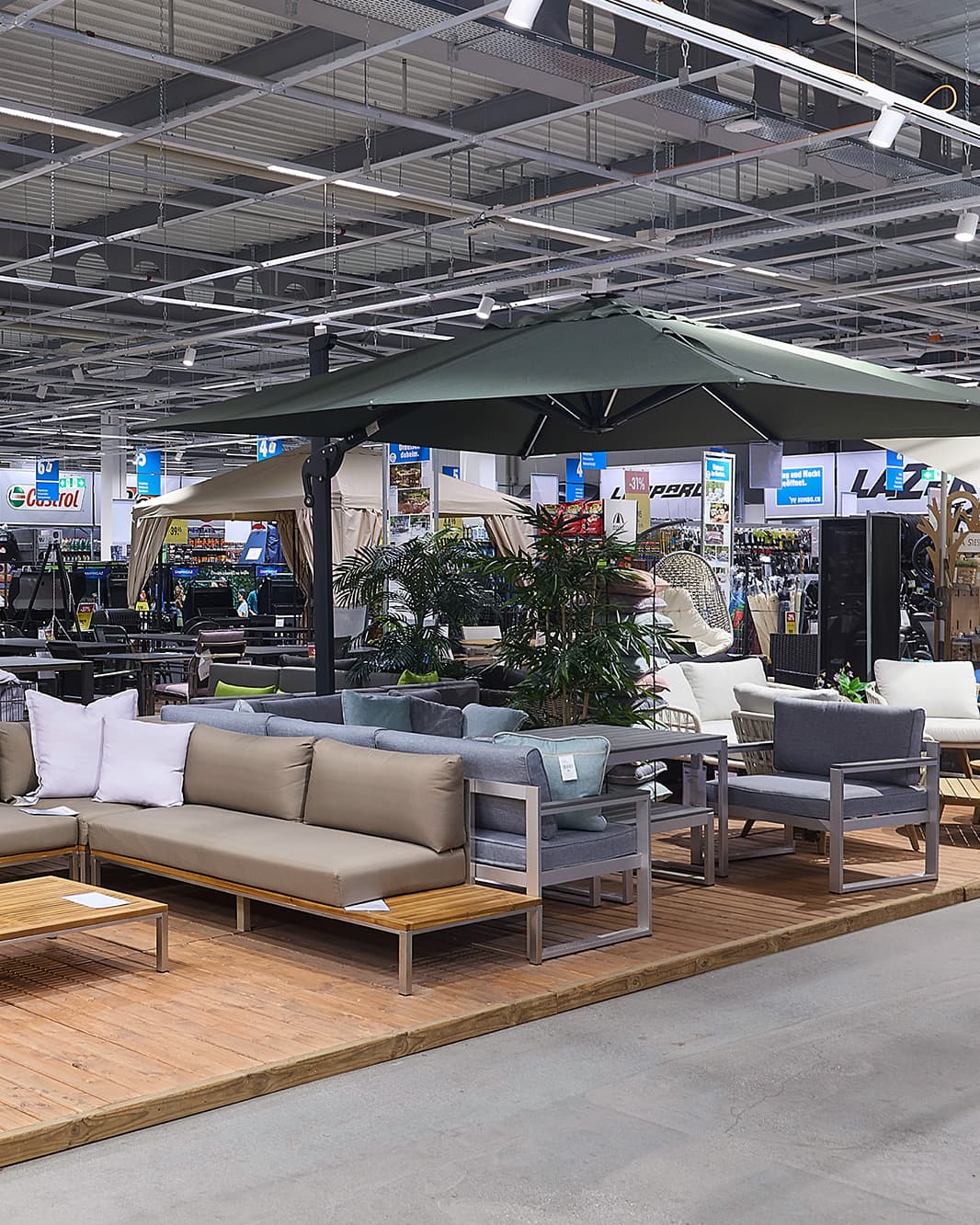 Gartenmöbel mit Loungesofas, Sesseln und grossem Sonnenschirm im JUMBO bei The Yards in Rümlang.
