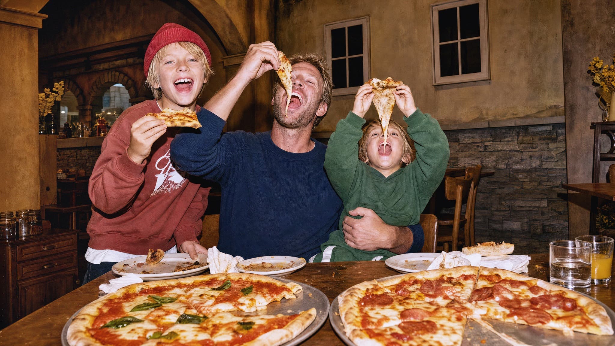 Ein Vater und zwei Jungen geniessen gemeinsam Pizza im Restaurant Piazza Meraviglia bei The Yards in Rümlang.
