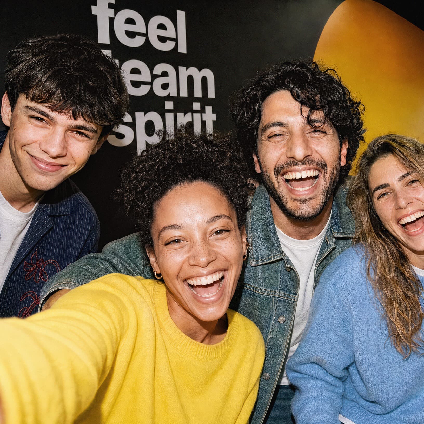 Vier lachende Personen rücken vor dem Schriftzug «feel team spirit» bei The Yards für ein gemeinsames Selfie zusammen.
