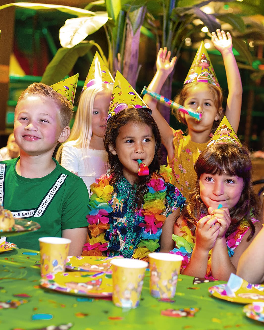 Fünf Kinder feiern mit bunten Partyhüten und Tröten einen Kindergeburtstag im Monkey Town bei The Yards in Rümlang.