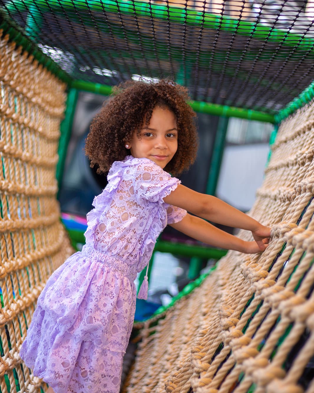 Mädchen in einem fliederfarbenen Kleid klettert über ein Seilnetz im Monkey Town bei The Yards in Rümlang.