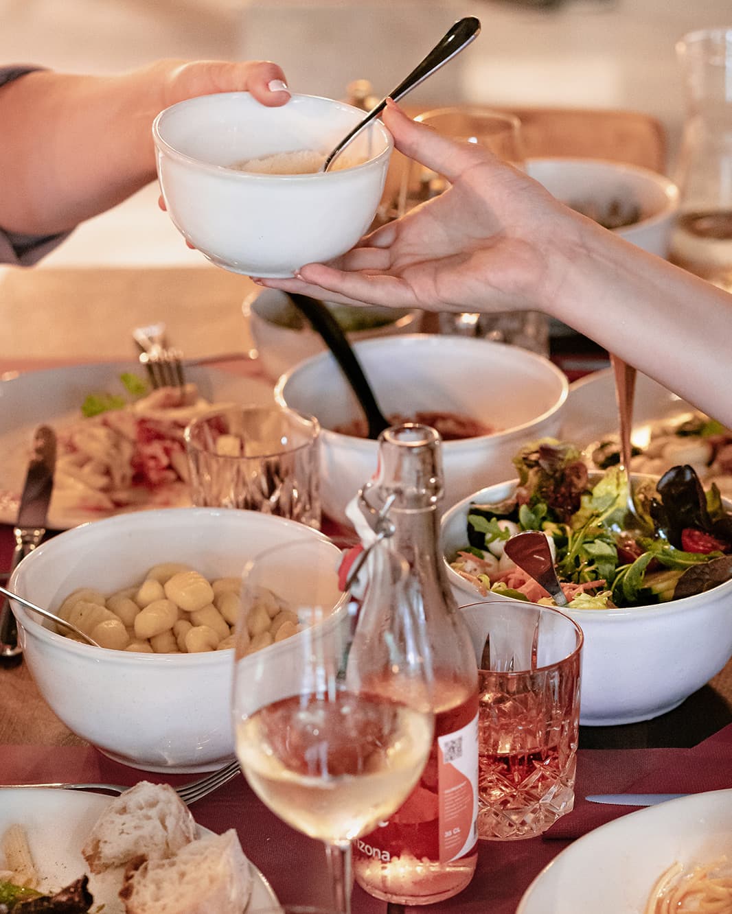 Gäste reichen sich Schüsseln mit italienischen Gerichten an einer gemeinsamen Tafel im Ristorante Piazza Meraviglia bei The Yards in Rümlang.