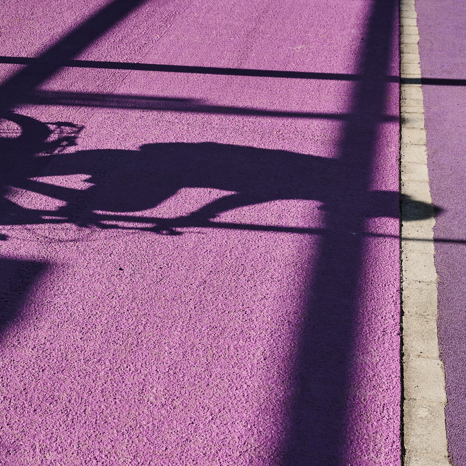 Sonnenlicht wirft markante Schatten auf den violetten Bodenbelag im Aussenbereich von The Yards in Rümlang.