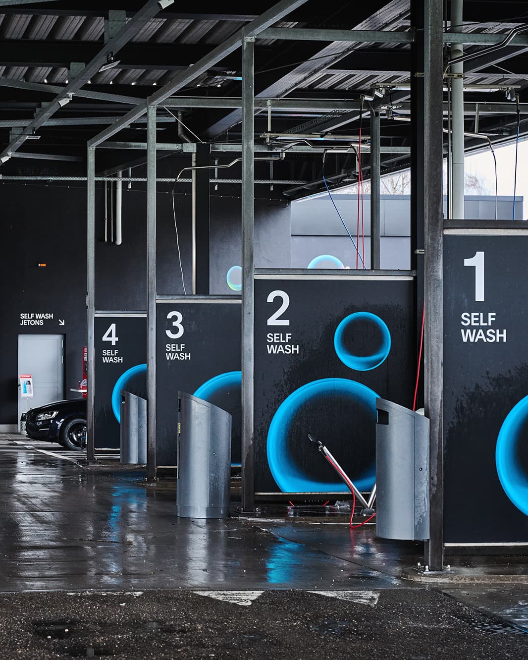 Vier nummerierte Self-Wash-Waschplätze mit Waschlanzen unter dem überdachten Dach bei The Yards in Rümlang.