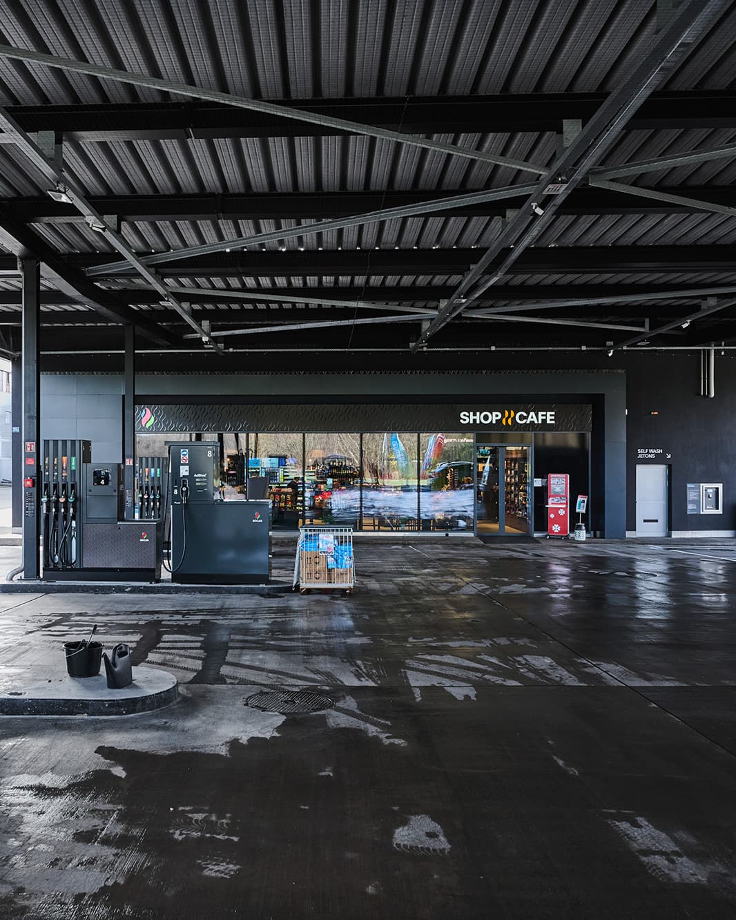 Blick vom Vorplatz auf die SOCAR Zapfsäulen und den Eingang zum Shop & Café bei The Yards in Rümlang.