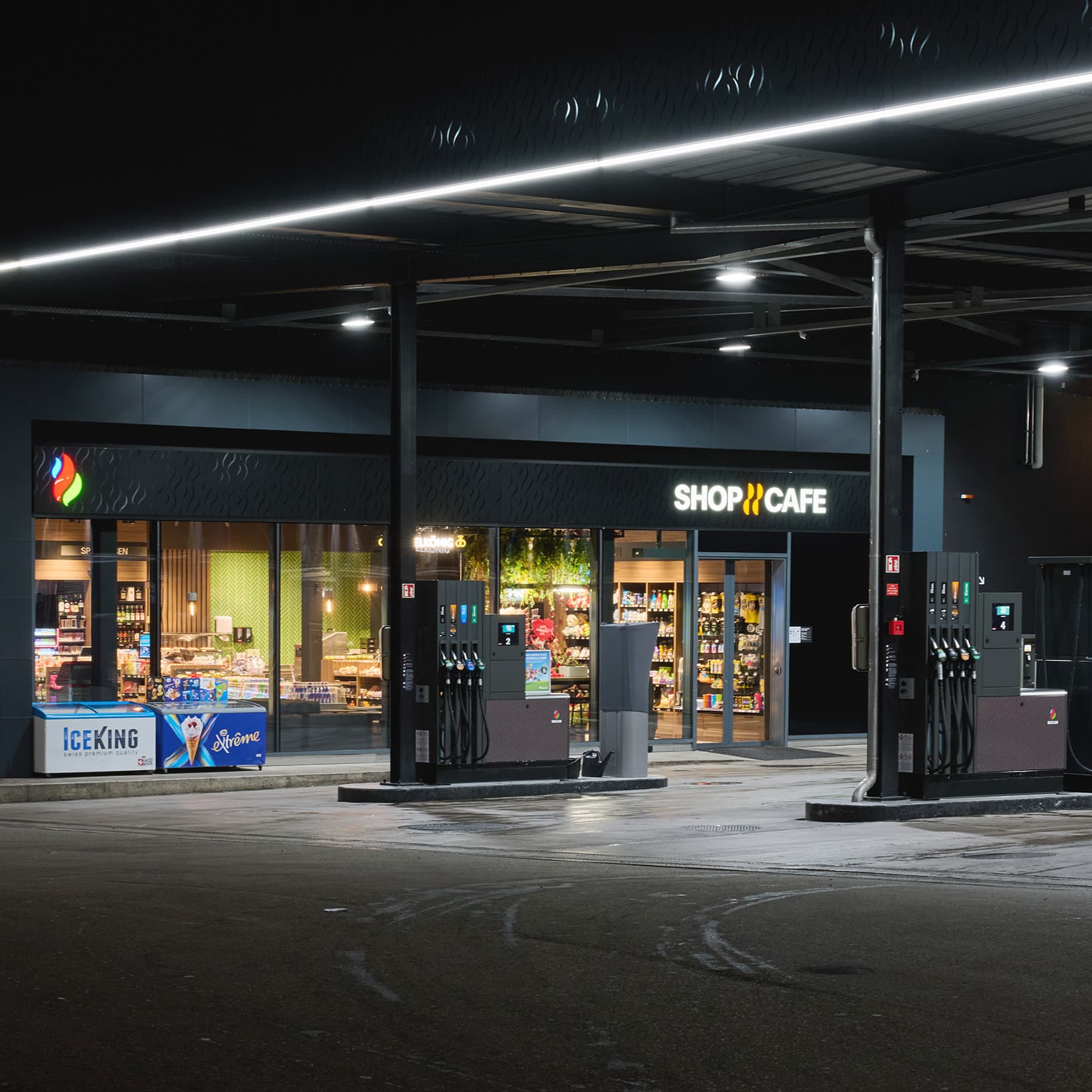 Beleuchteter SOCAR Shop & Café und Zapfsäulen an der Tankstelle bei The Yards in Rümlang.